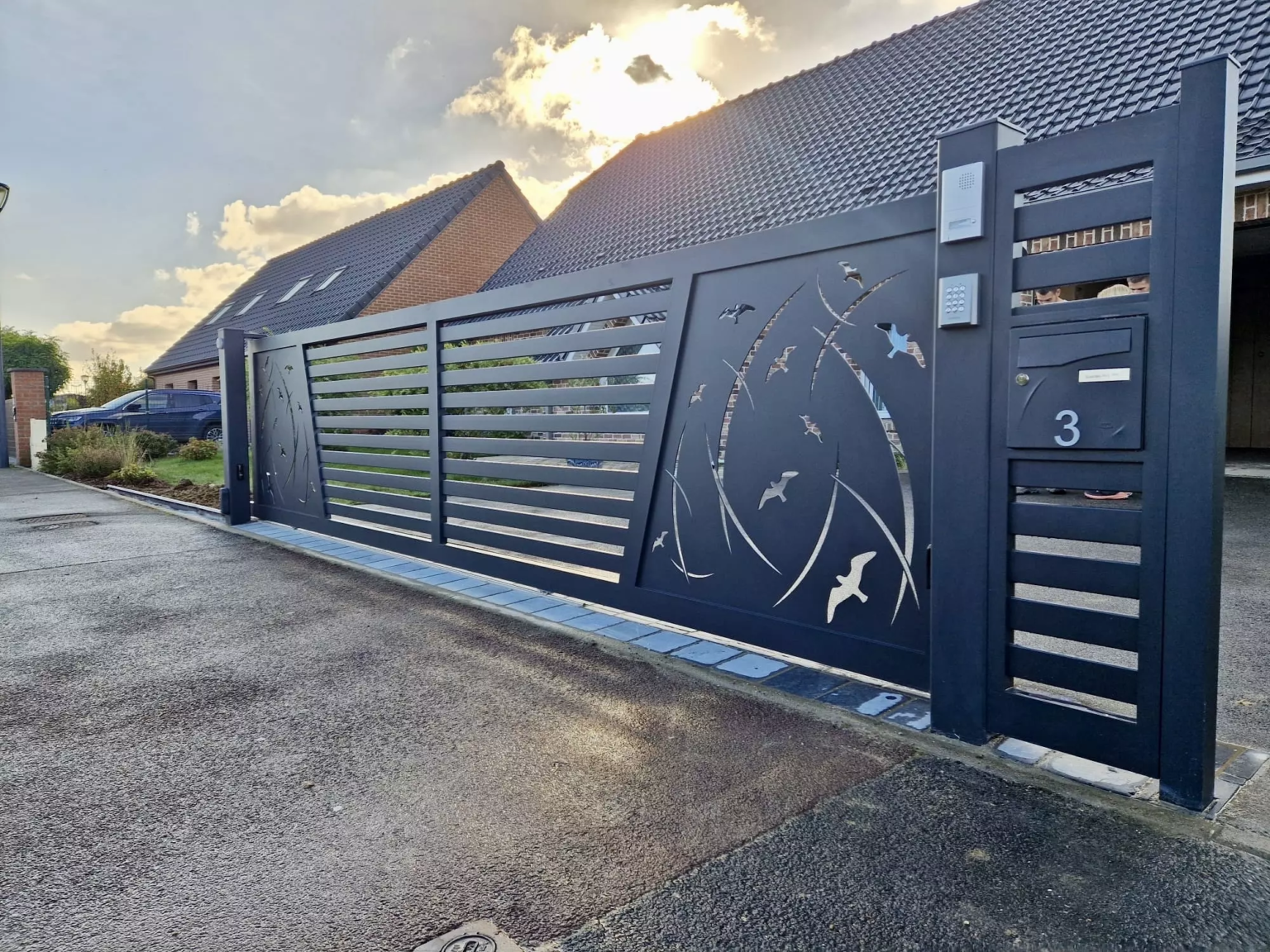 Portail coulissant motorisé et portillon en aluminium gris anthracite, création sur mesure avec découpe laser oiseaux et lignes dynamiques, installé dans le Nord de la France. Fabrication française Eurofactory